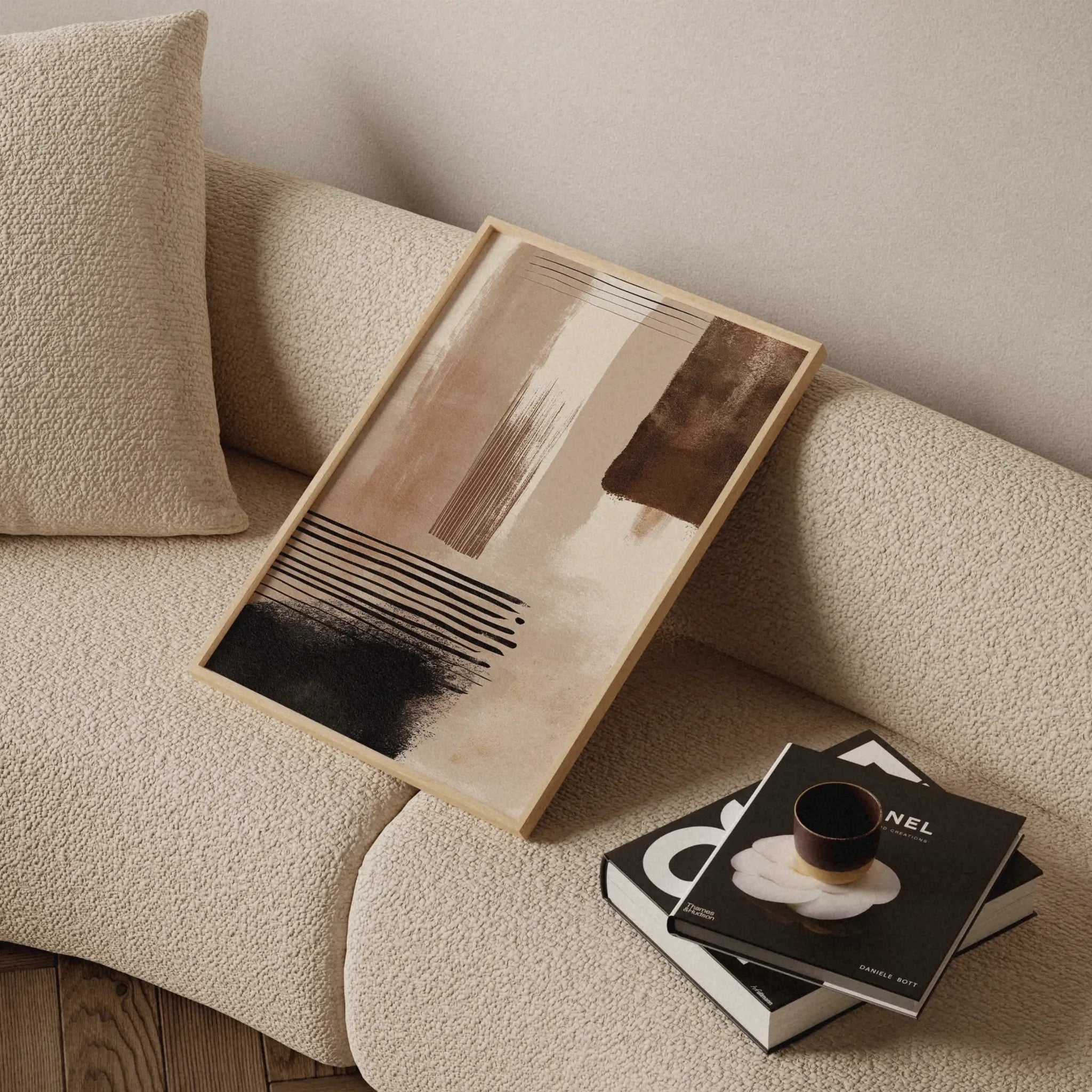 Abstraktes Poster in Beige, Braun und Schwarz aus der Sand & Coal Kollektion als modernes Wandbild im Holzrahmen auf hellem Sofa von Veróme